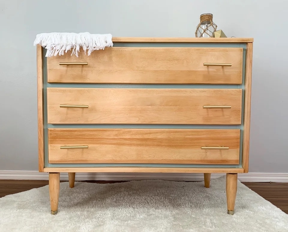The dresser after with a gray-blue accent and gold drawer handles