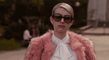 Emma Roberts in a fur coat and big sunglasses pouts.