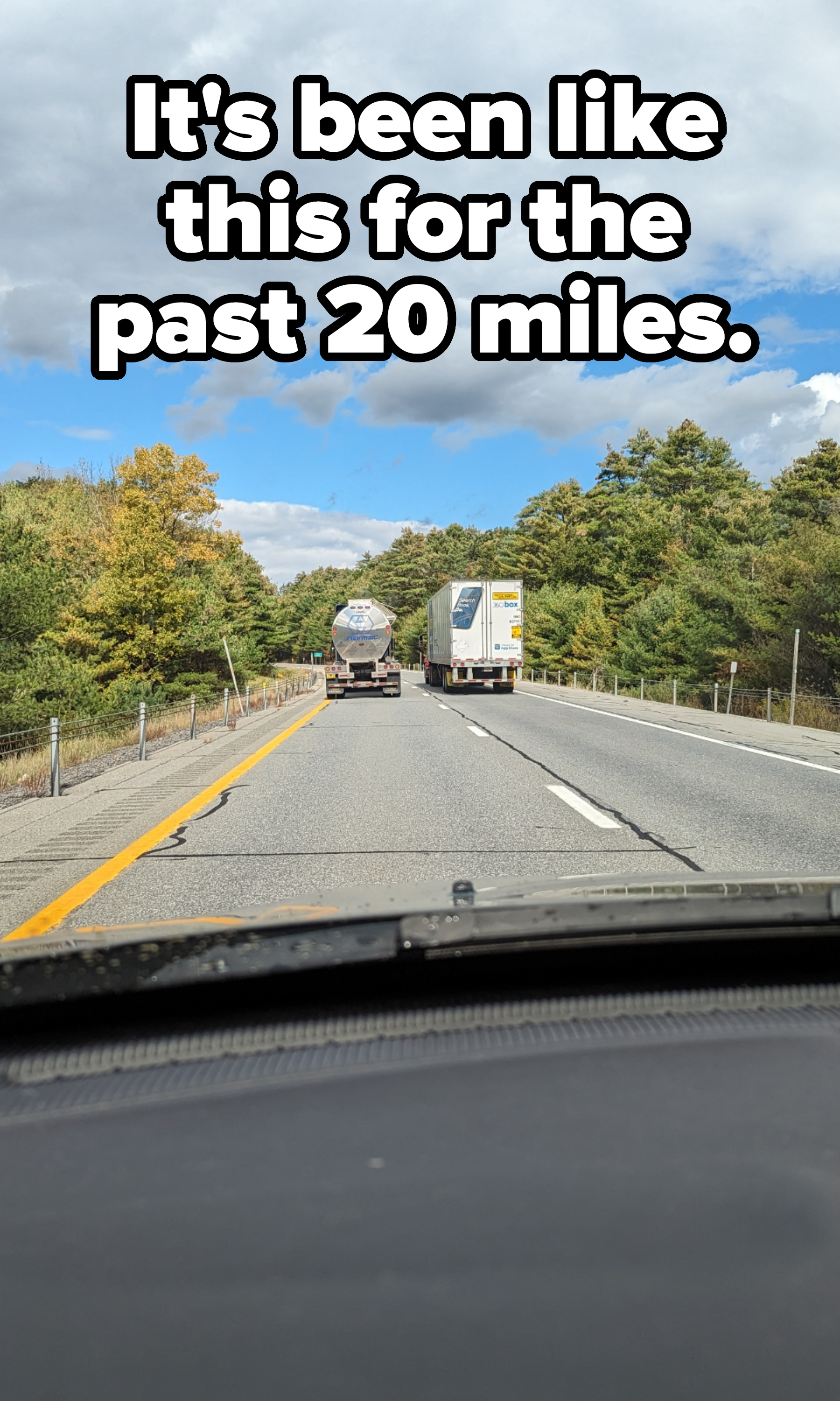 Two parallel trucks on a two-lane road as seen from the driver&#x27;s seat of a car behind them, with caption, &quot;It&#x27;s been like this for the past 20 miles&quot;