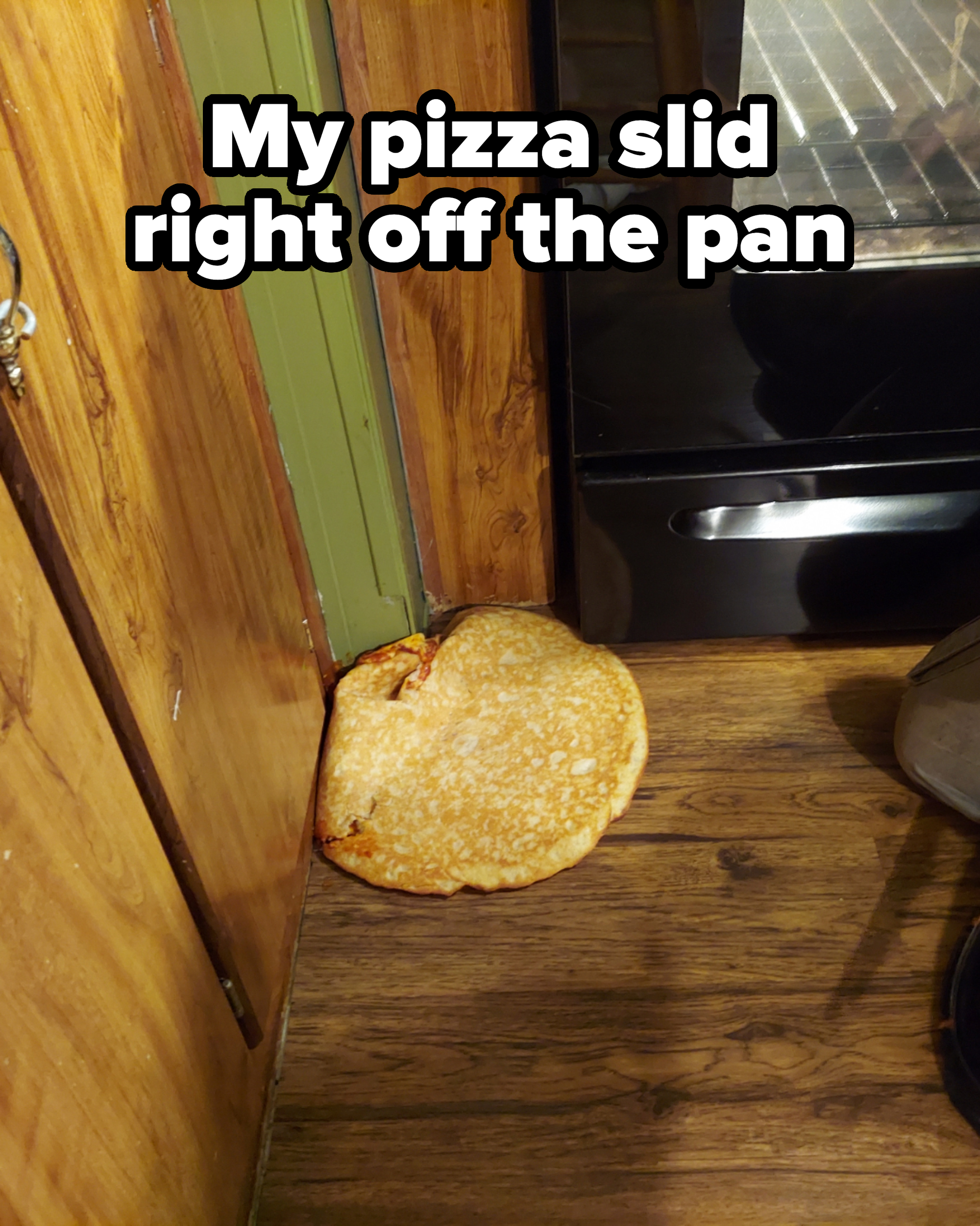 Pizza on the floor in front of an oven, with caption, &quot;My pizza slid right off the pan&quot;