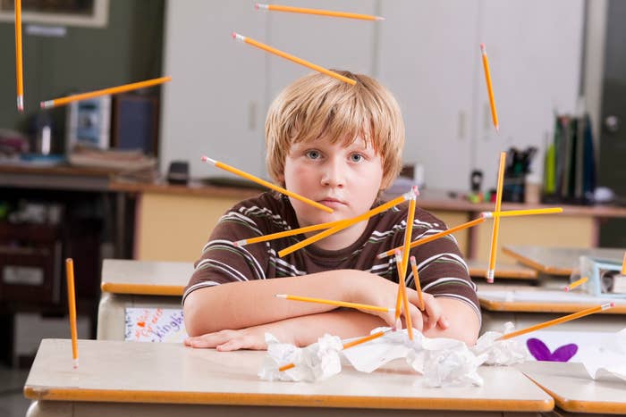 A little boy throwing pencils in class