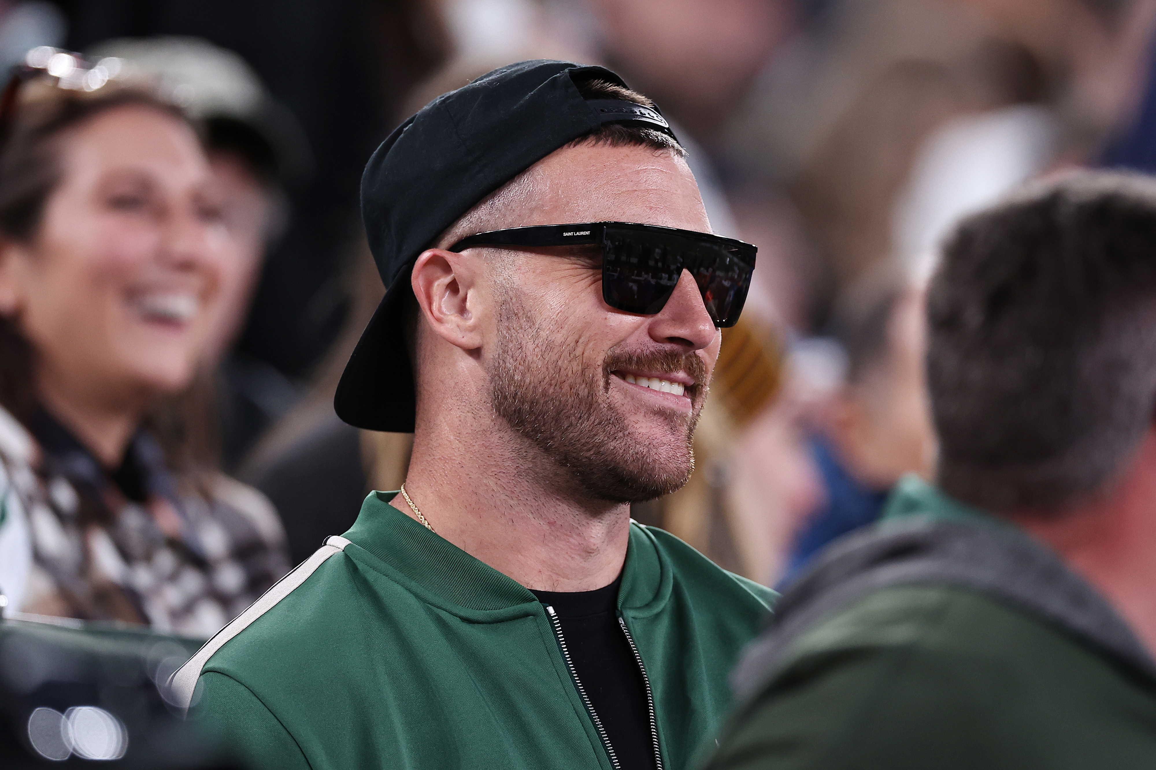 Close-up of Travis smiling and wearing a cap backward and sunglasses