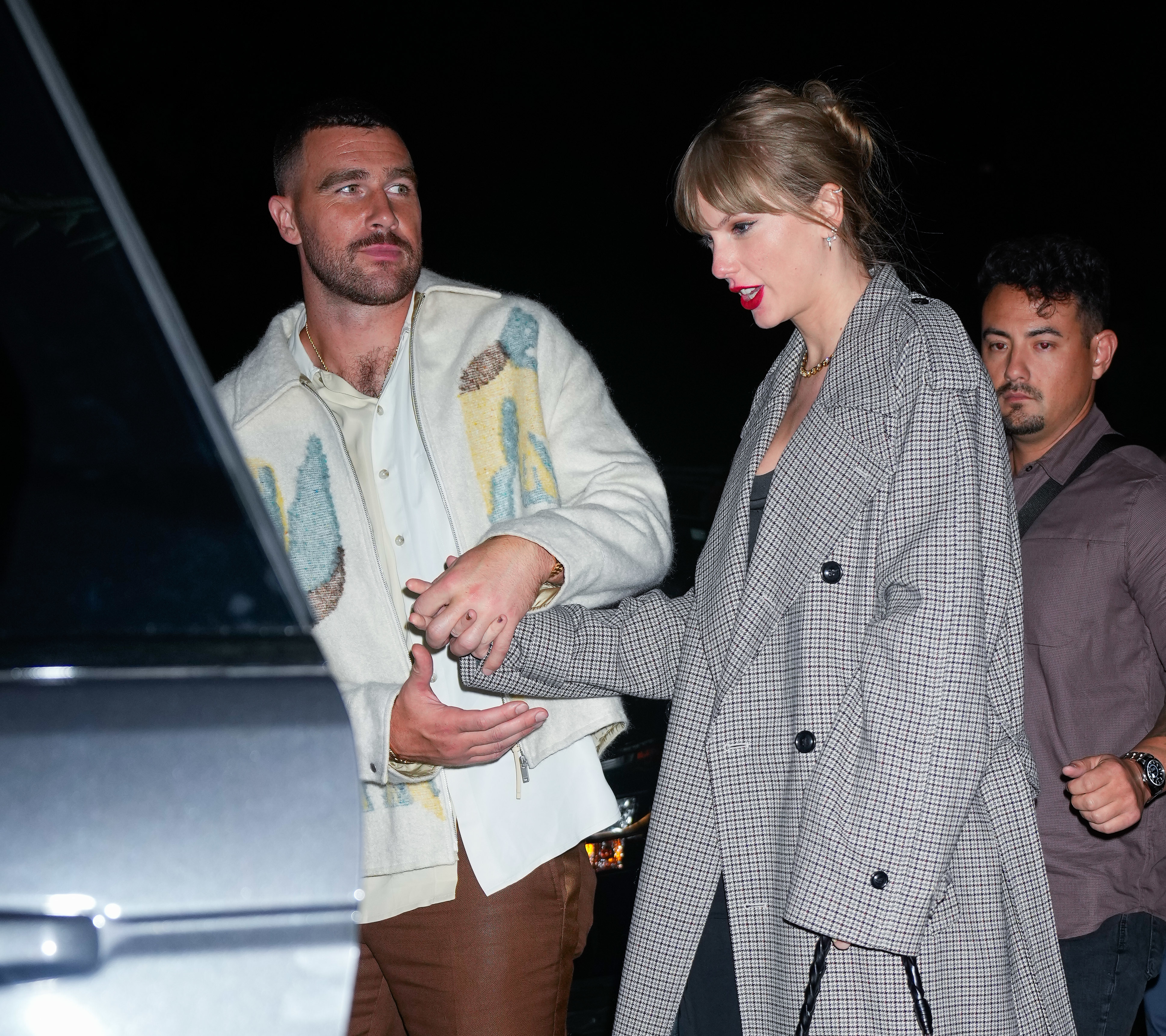 Close-up of Taylor and Travis holding hands at a car