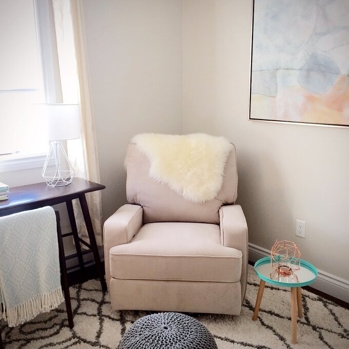 Cozy chair with plush throw, side table with lamp, and a small table