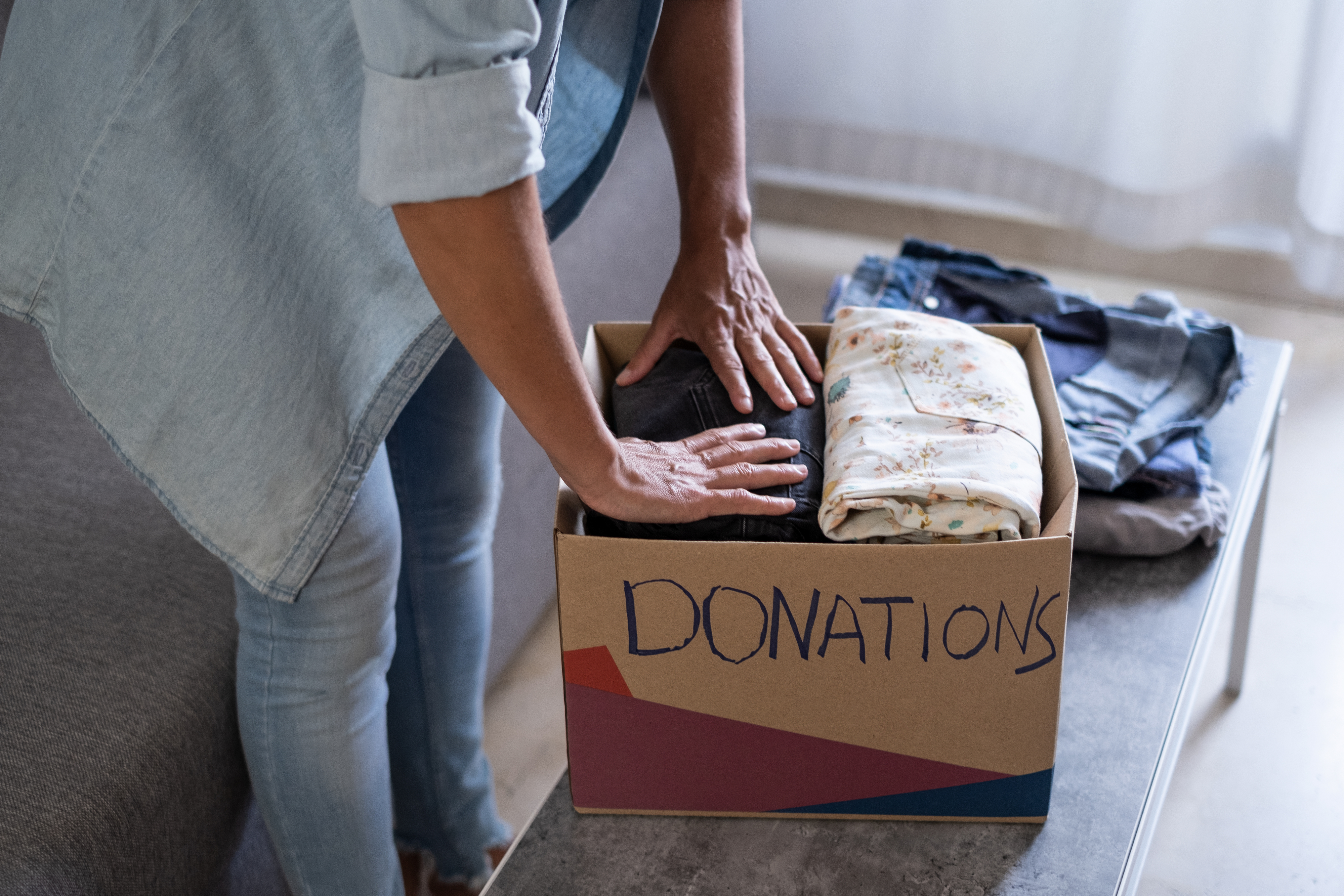 Someone putting clothing in a donation box