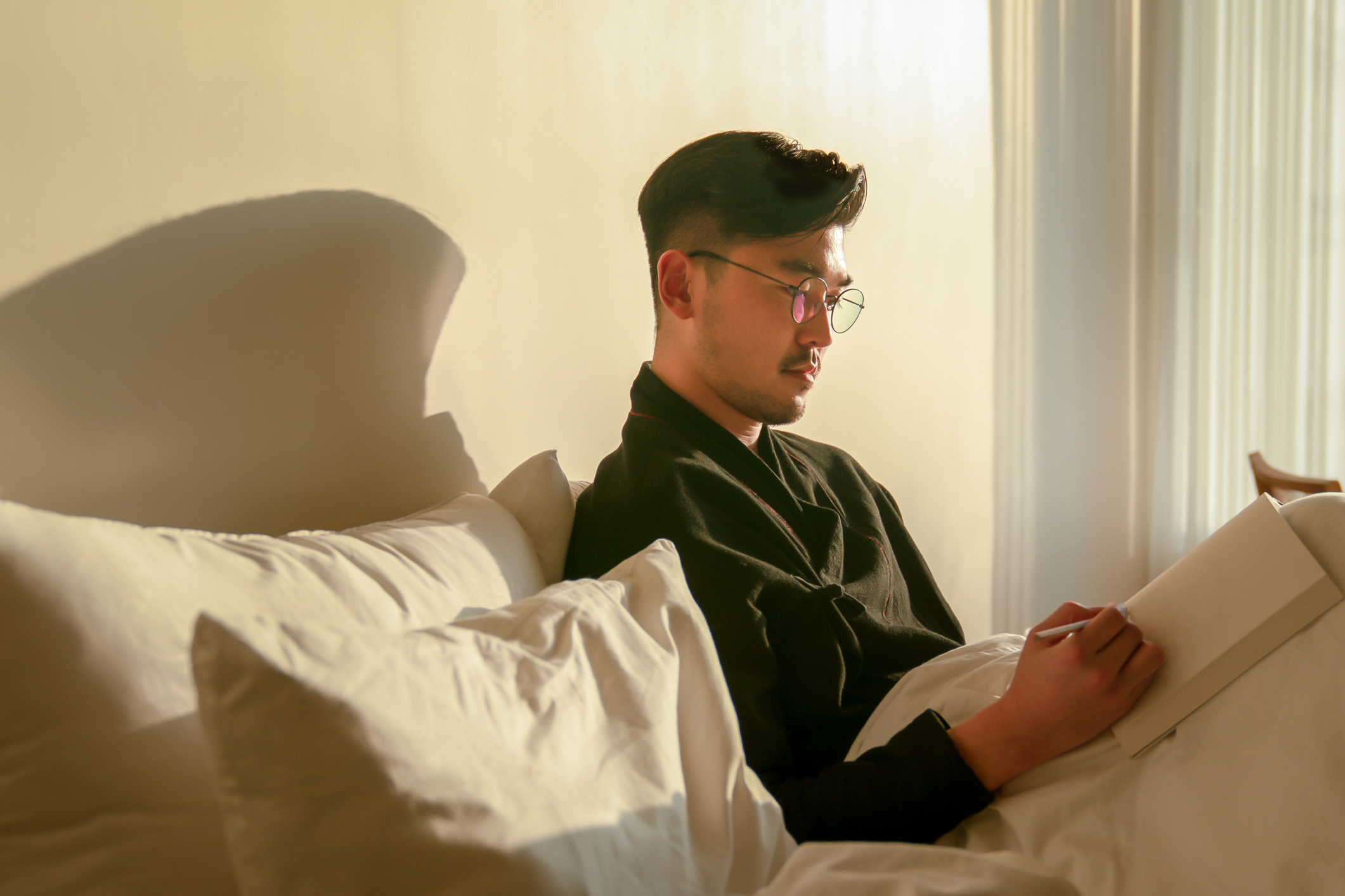 A man is in bed, journaling