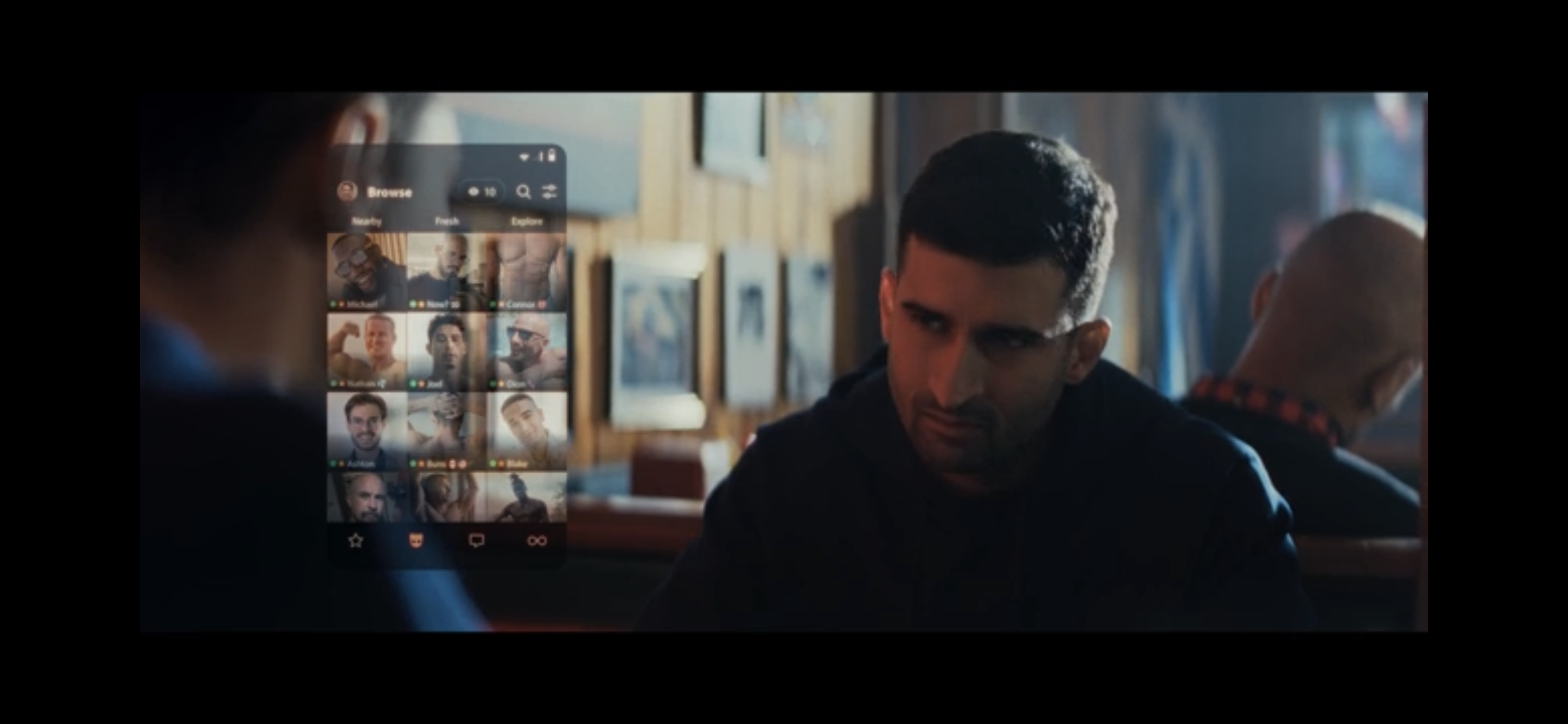 An upset man with Grindr images onscreen