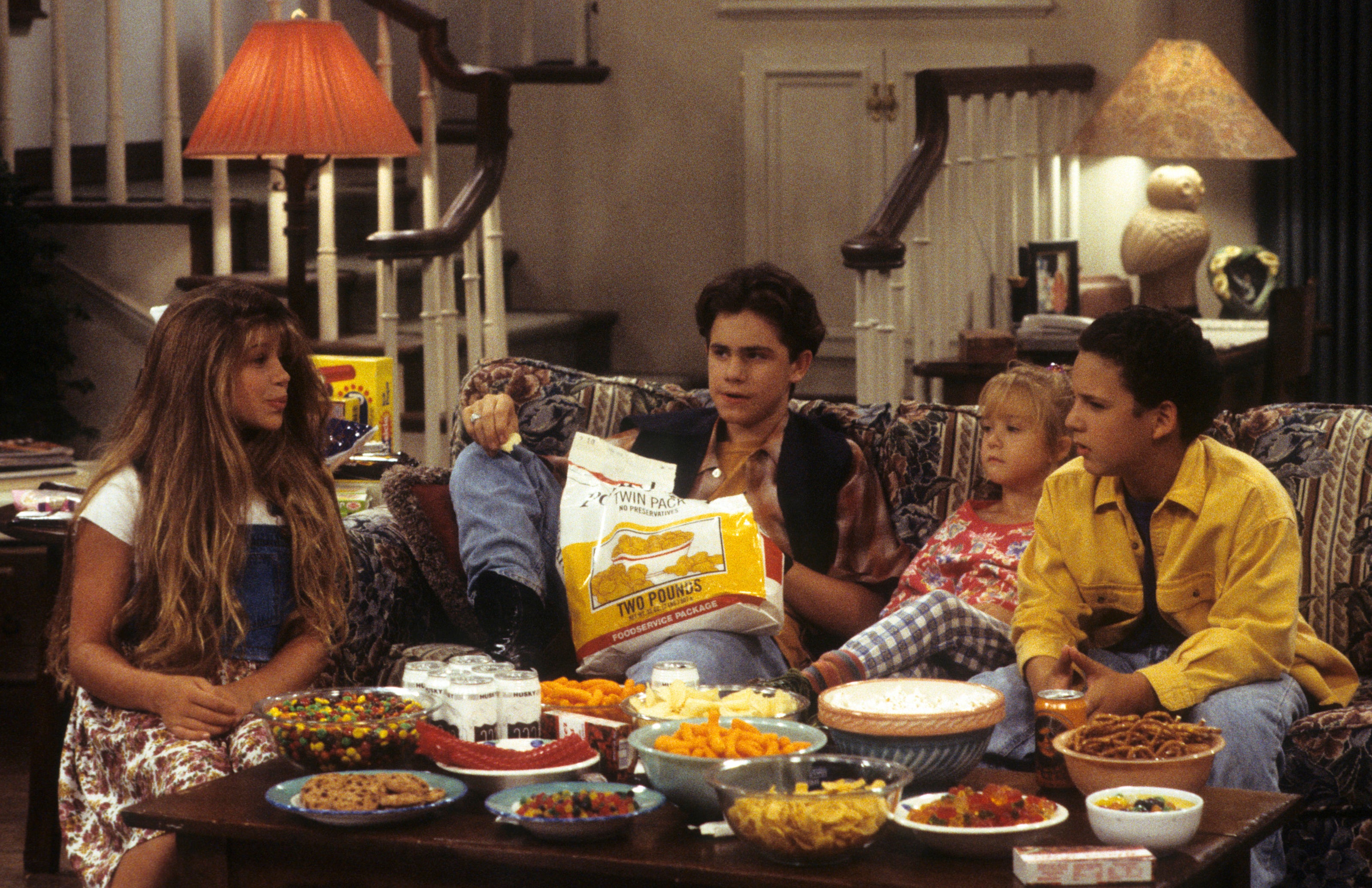 the young children on set filming a scene in the living room with lots of snacks