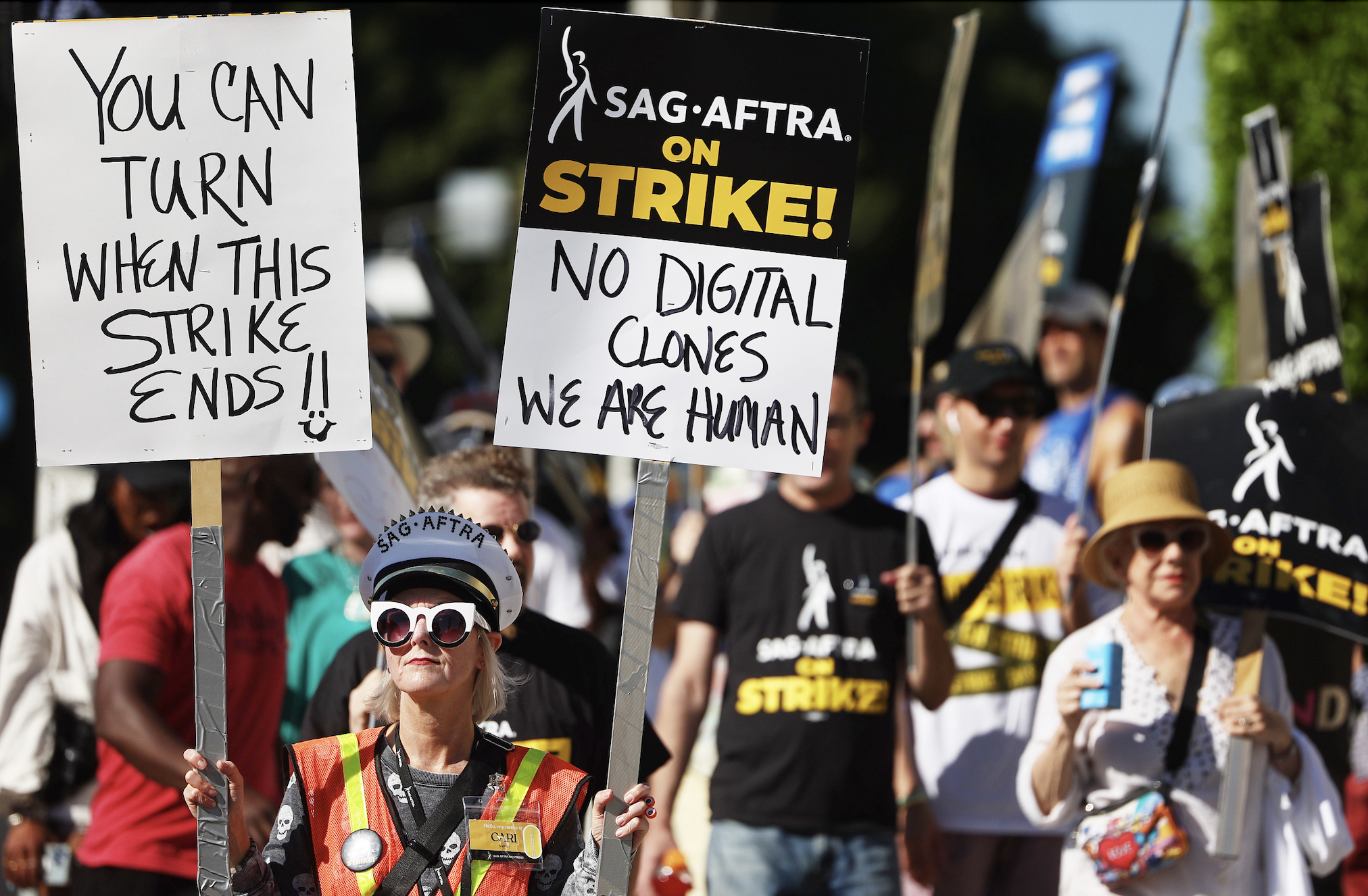 SAG AFTRA strikers with sign that says &quot;no digital clones, we are human&quot;