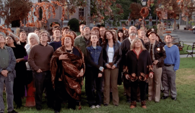 The people of Stars Hollow stand in the square looking up towards the sky.