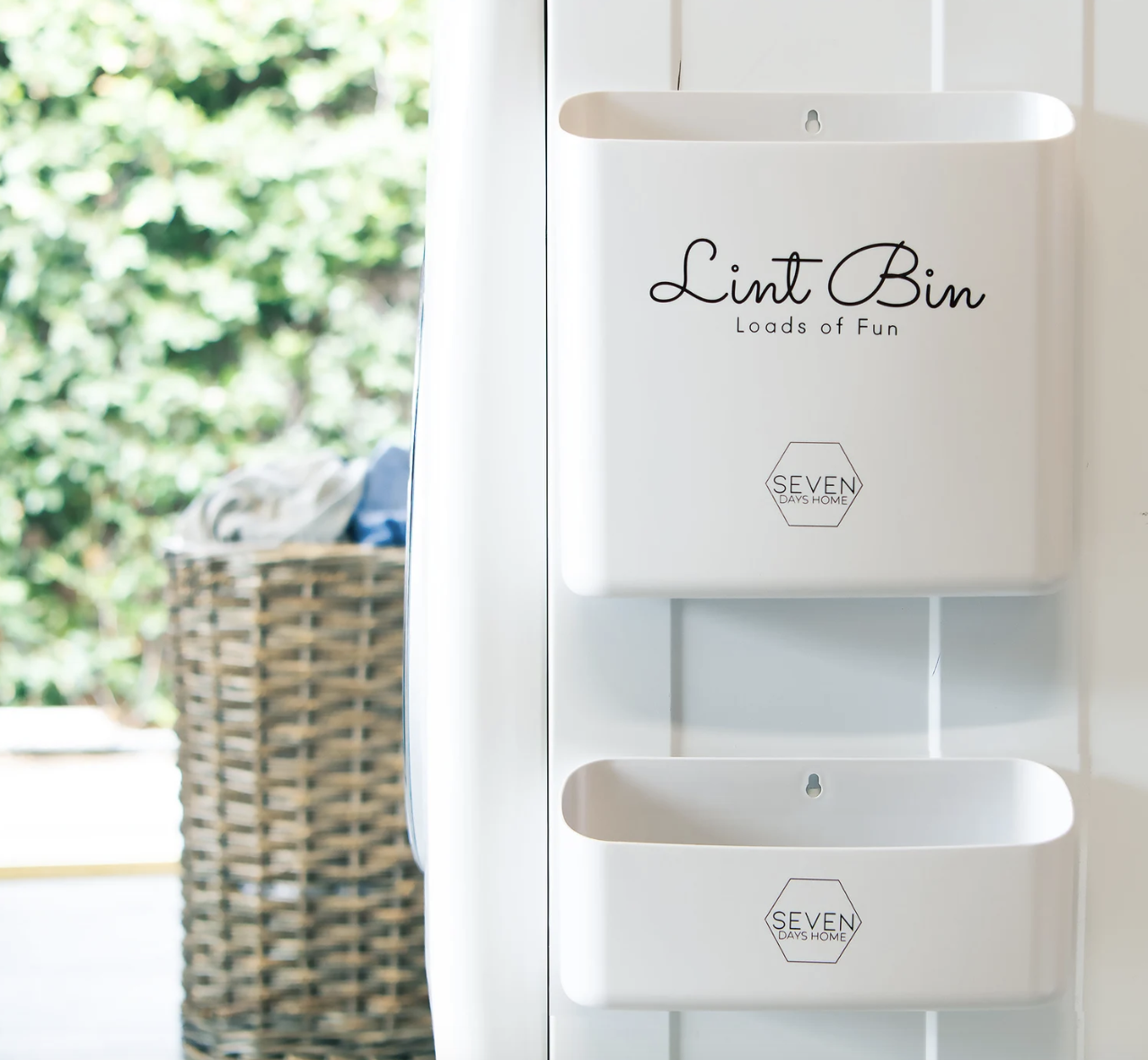 Two different-sized bins stuck to the side of a dryer with things inside