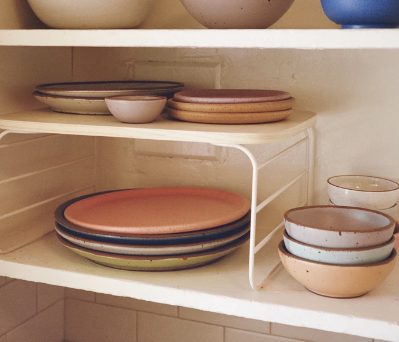 One shelf rises in a cabinet with plates underneath and more plates on top