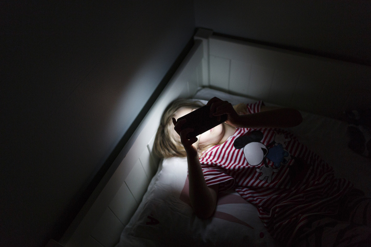 A person on their phone in bed in the dark