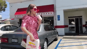 Gigi Hadid in a sparkly dress holds In-N-Out bag out to the camera.