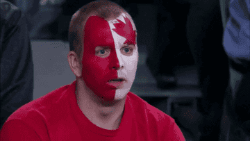 Man in Canadian face paint holds his head in distress.