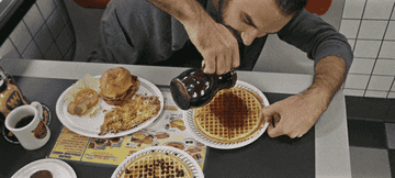 Man pours maple syrup on a waffle.