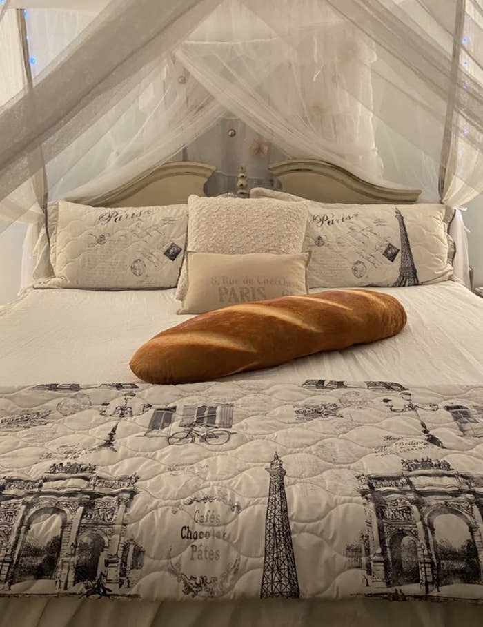 A Paris-themed room consists of bedsheets with prints of popular Parisian monuments in addition to a huge baguette pillow