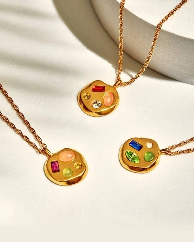 three gold pendants with different stones in each one
