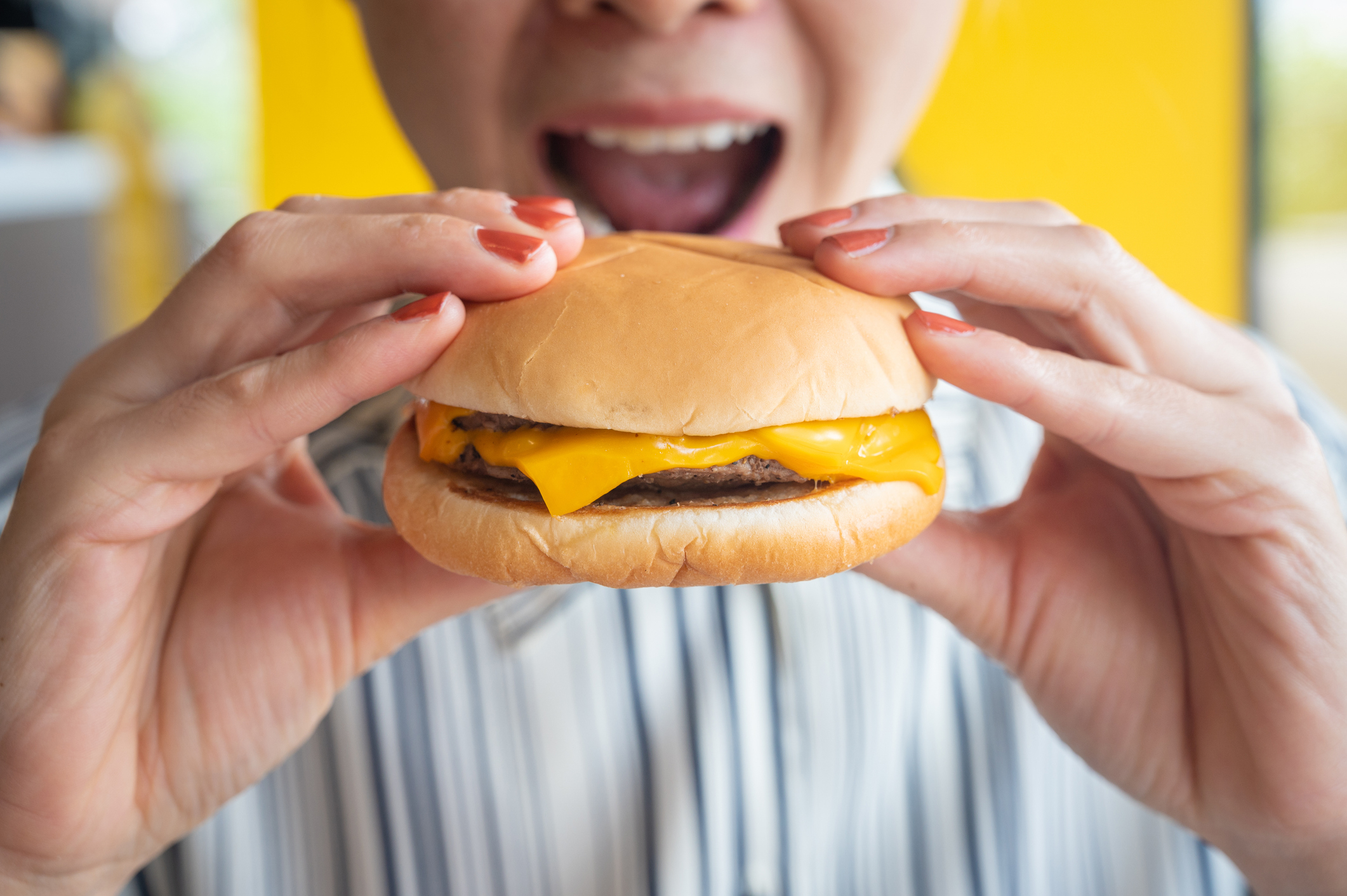 A woman about to bite a burger