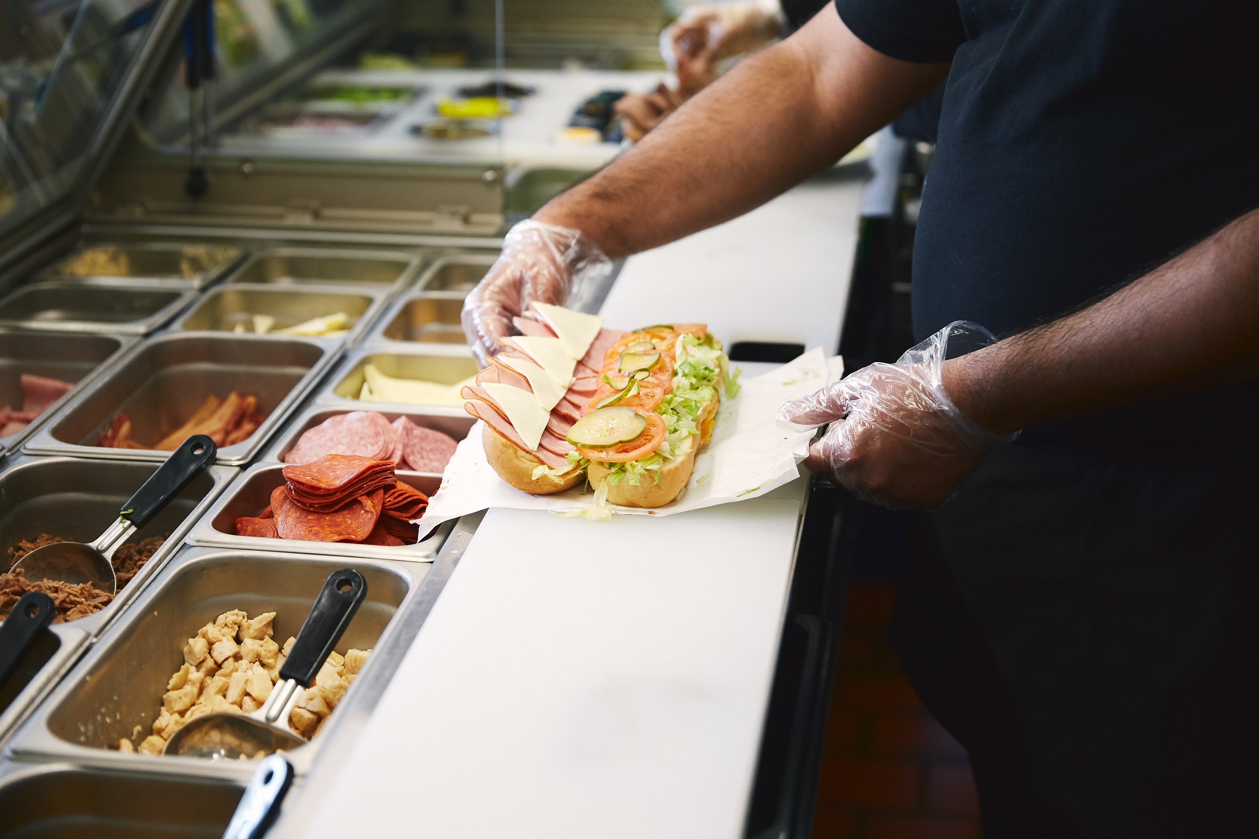 Someone making a sandwich at a sandwich shop