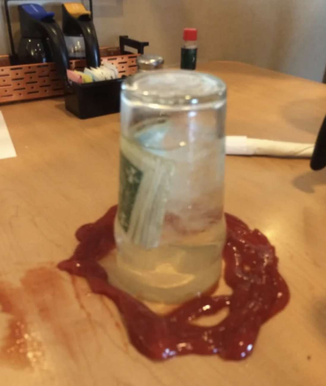 Money in a jar surrounded by ketchup