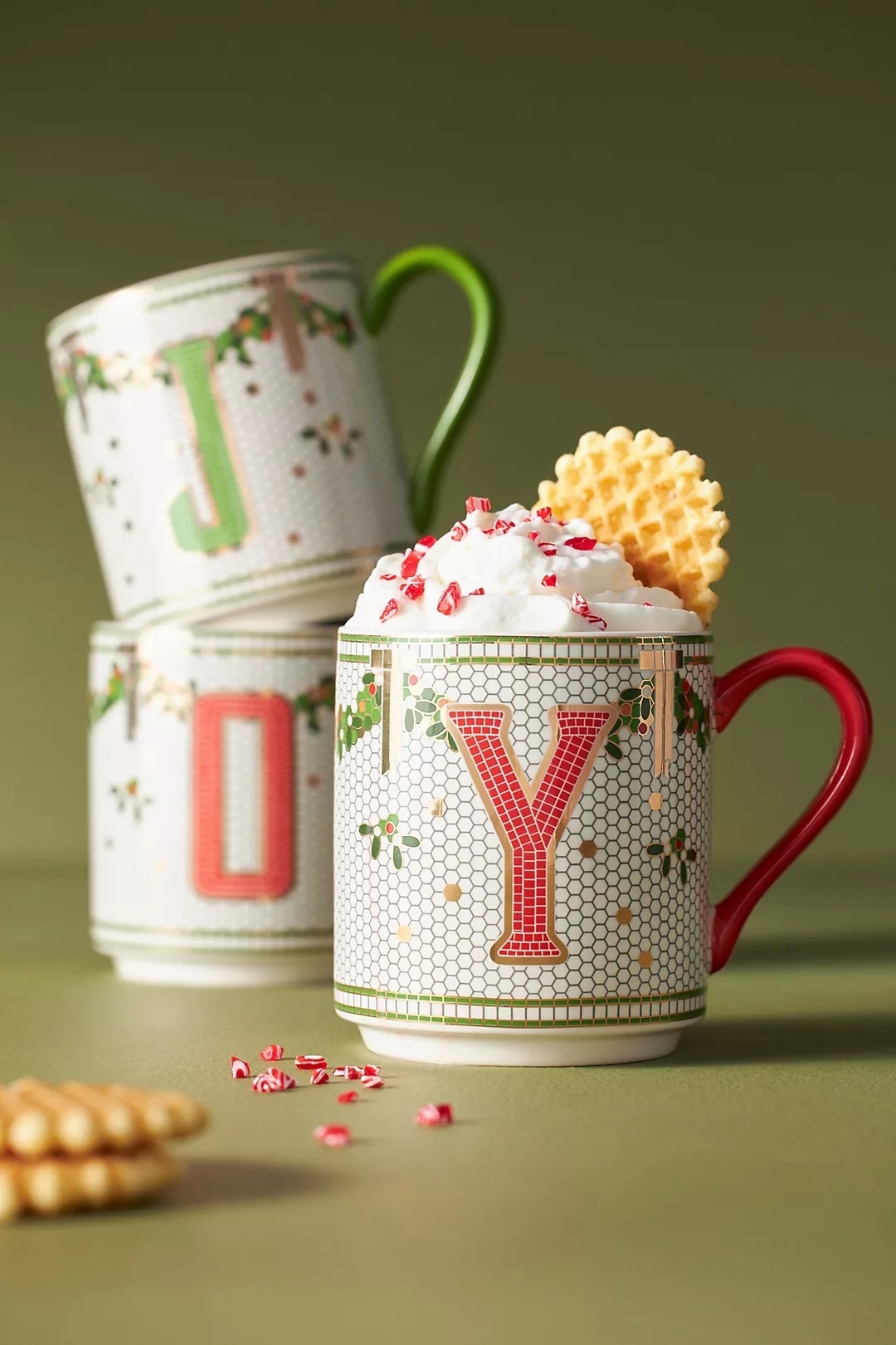 a tiled mug with holly on it and a red initial