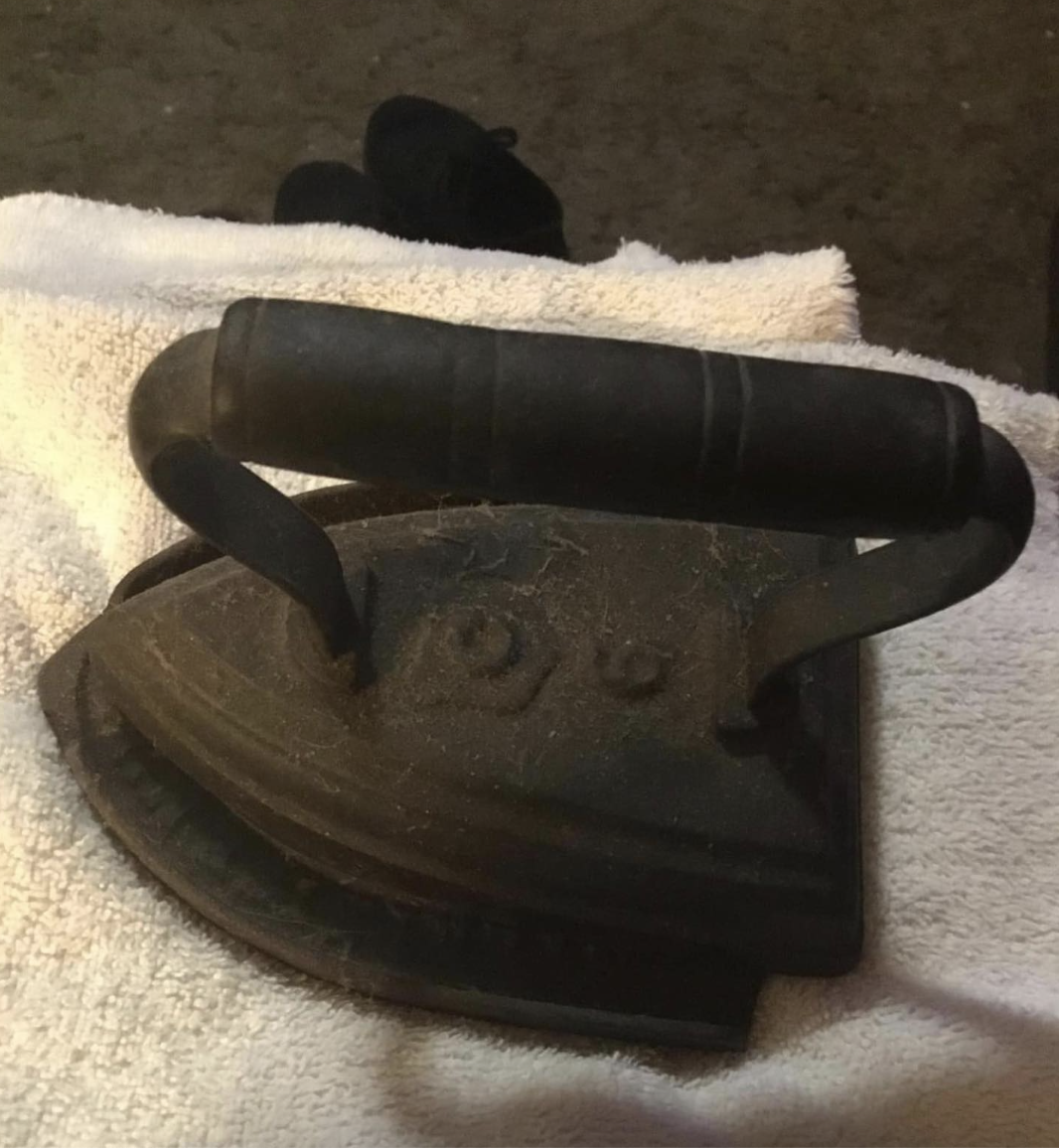 An antique cast-iron iron with large handle to be heated over fire