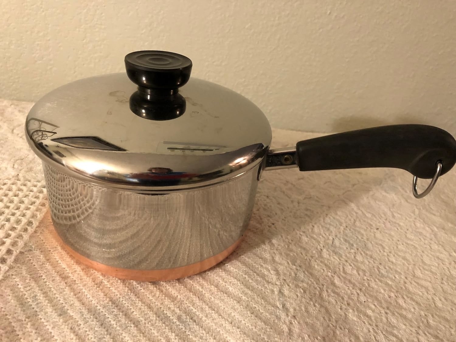 A stainless steel pot with a copper bottom and handle with cover