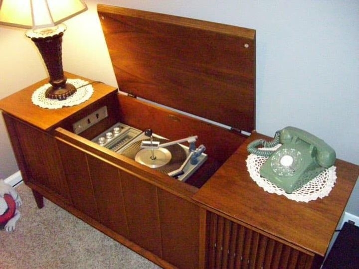 A turntable in a wooden cabinet with a rotary phone on it