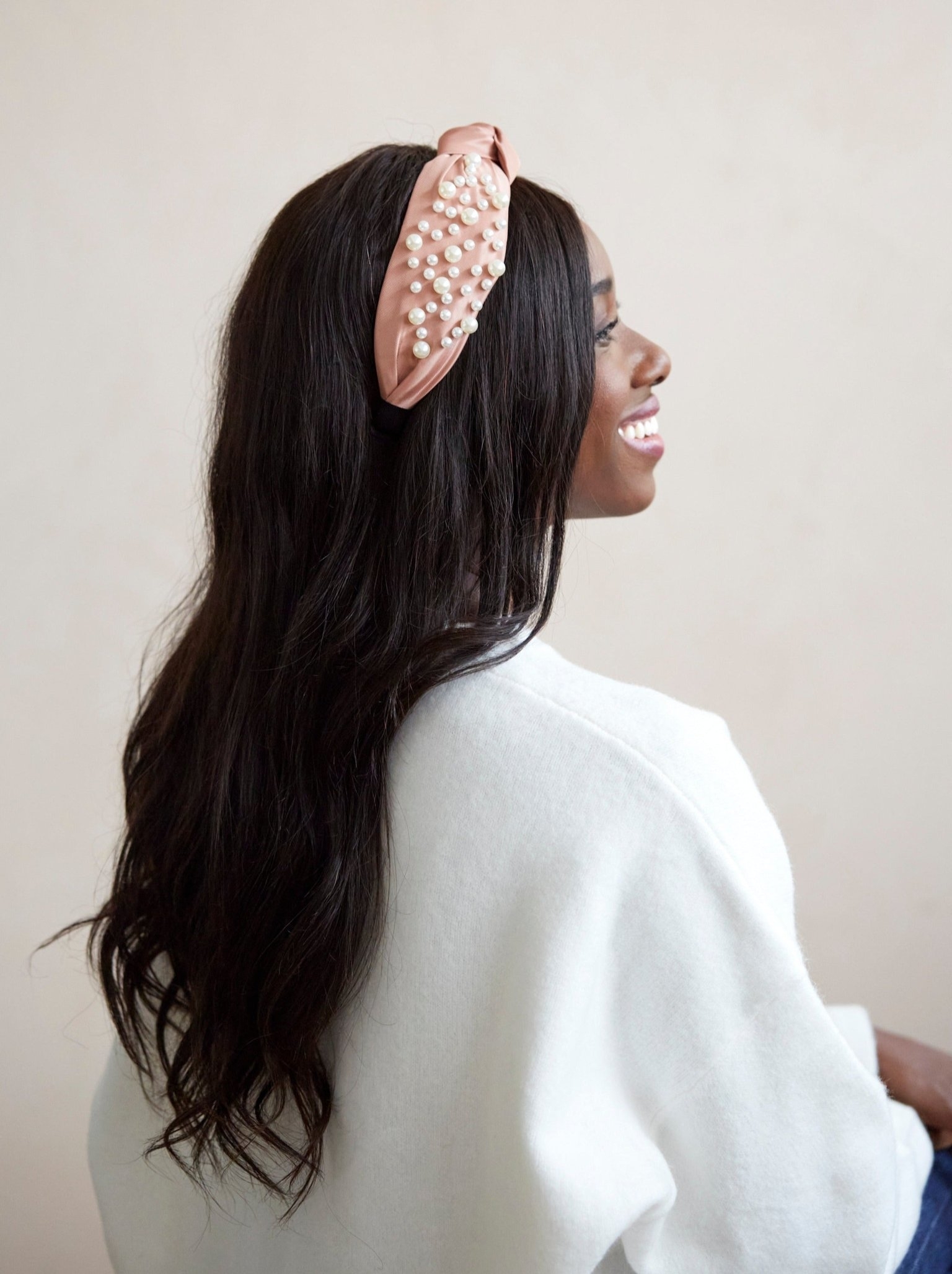a model wearing the blush colored headband with pearls on it