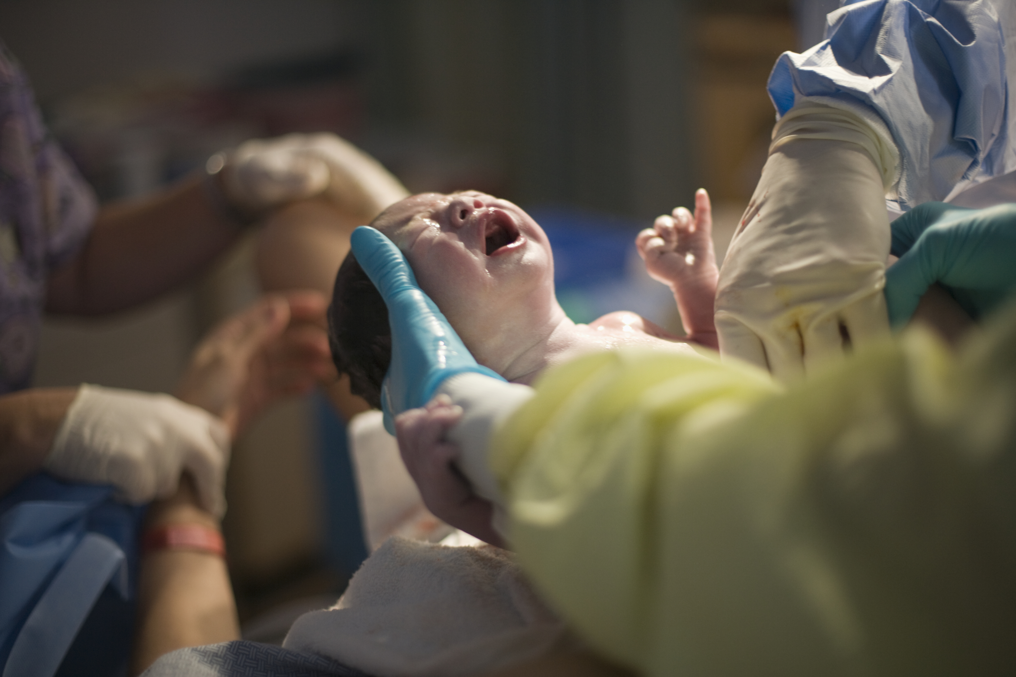 Doctors holding crying newborn