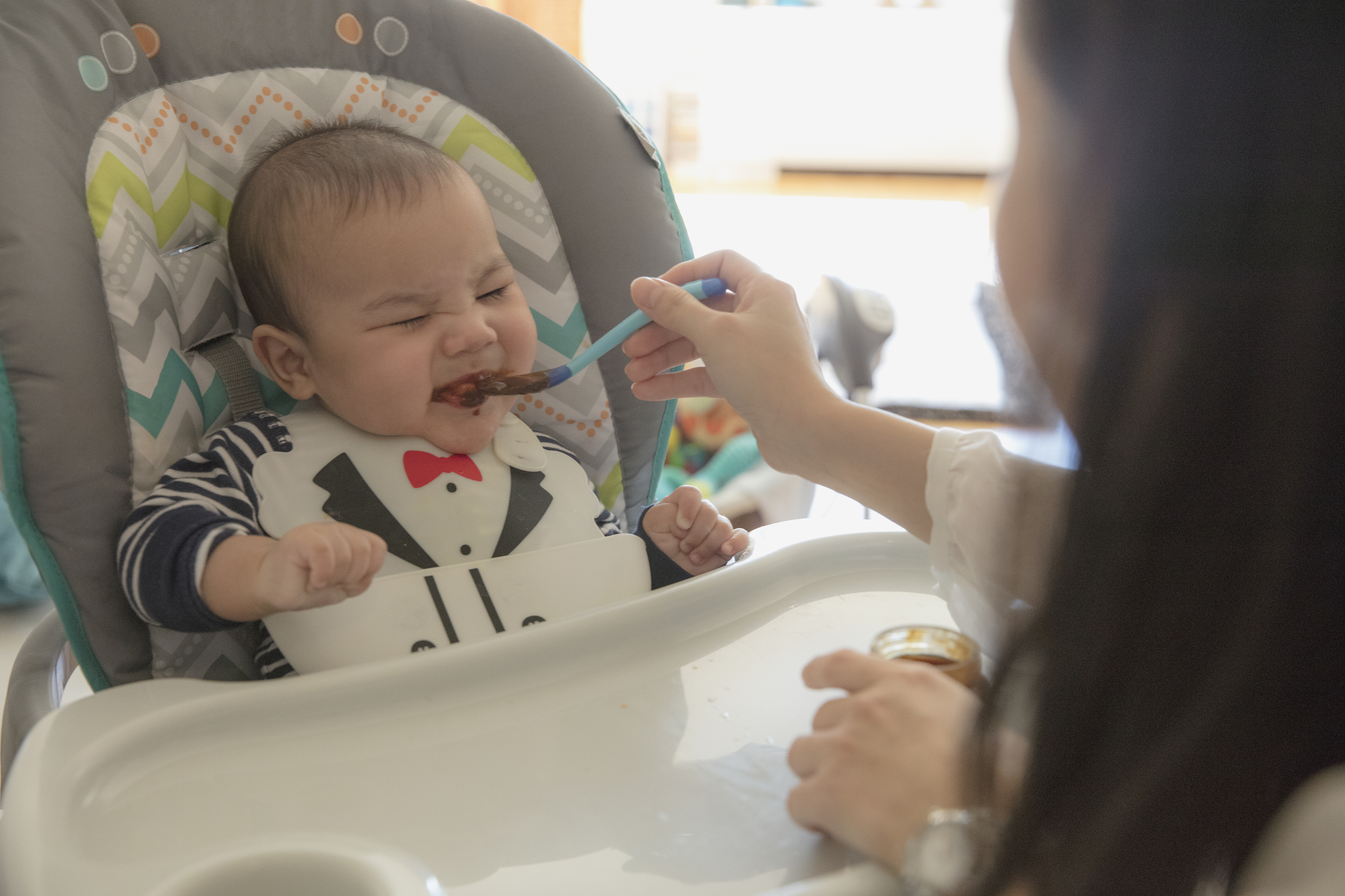 A mother feeding her baby in a high chair