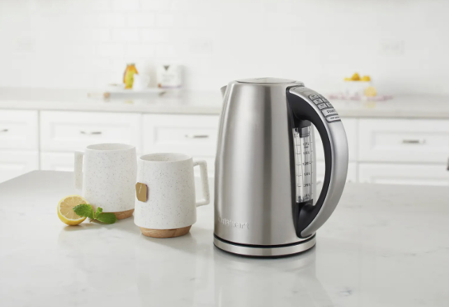 The kettle on countertop next to two mugs