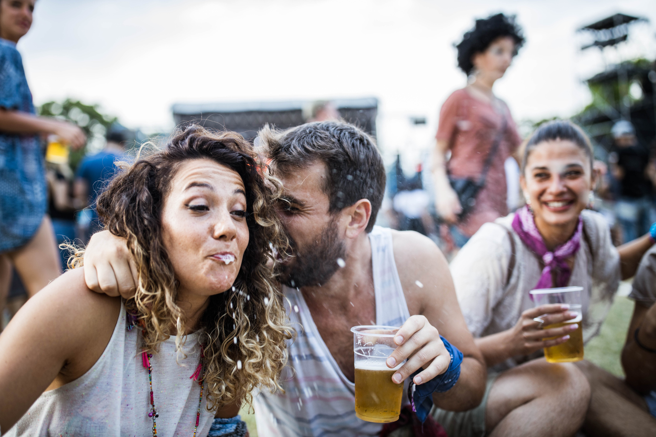 A woman spitting out beer as a man hugs her