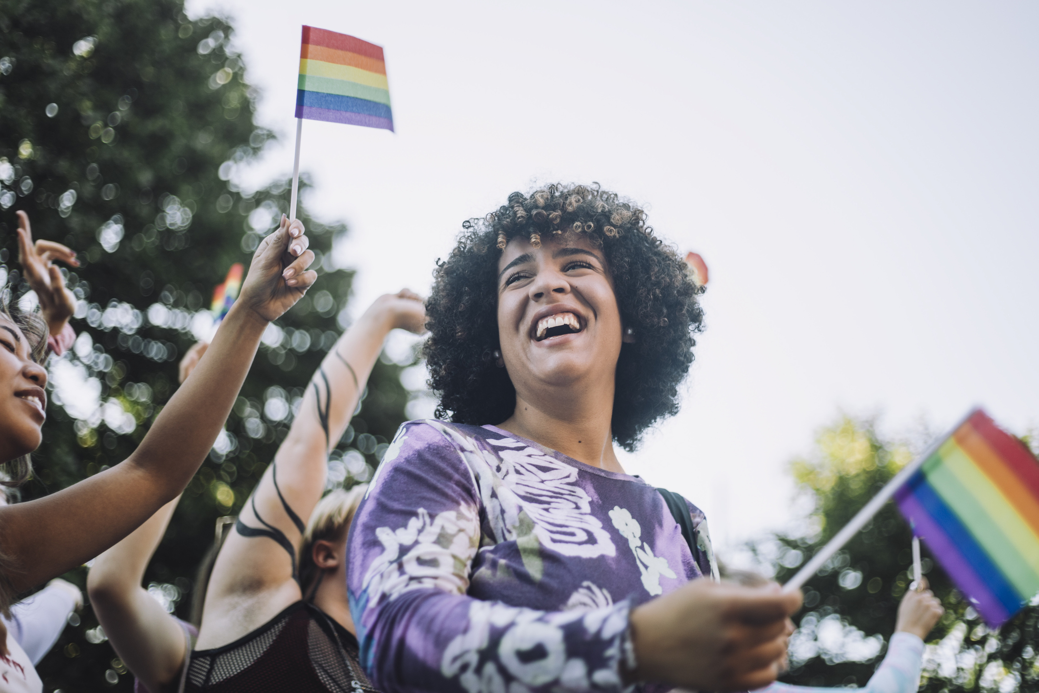 Smiling person waving a pride flag