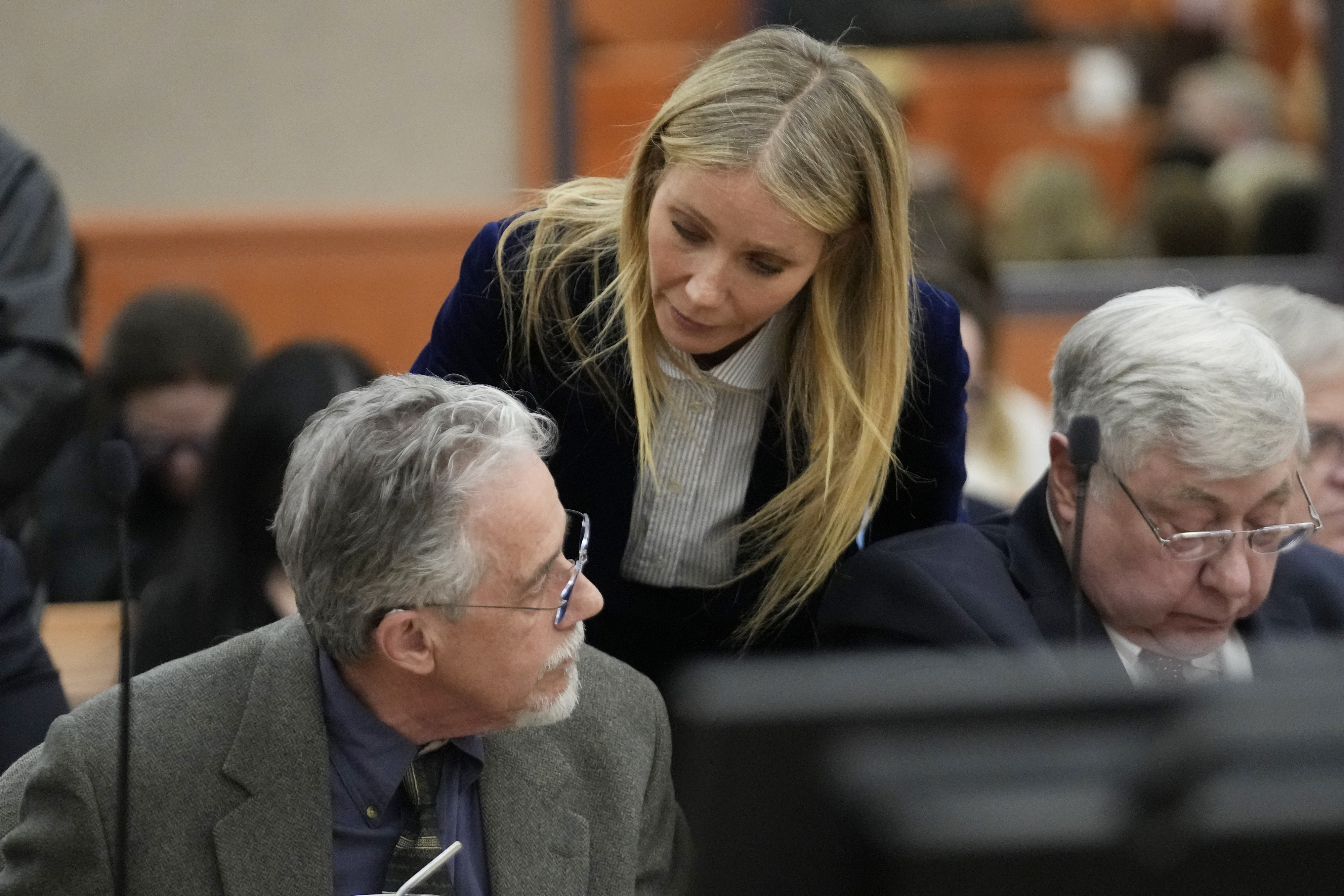 Gwyneth leaning over a seated Terry in court