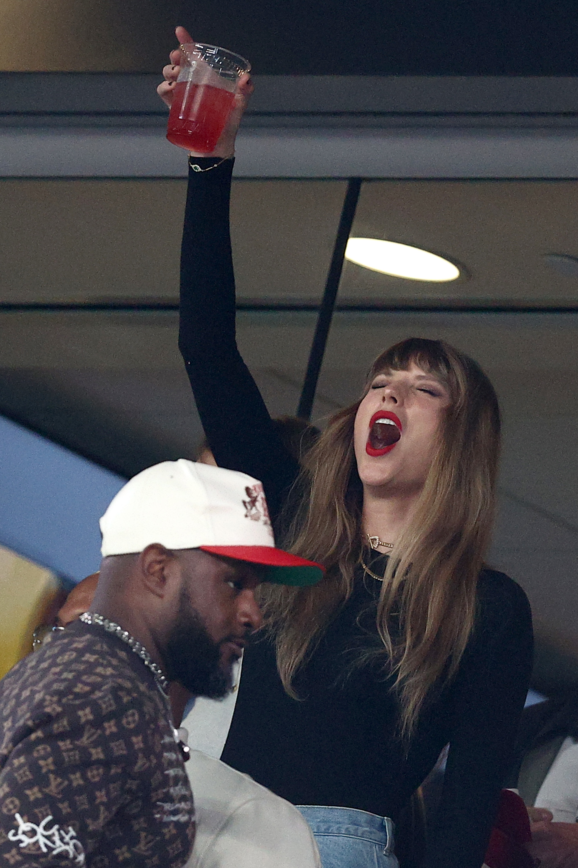 Taylor cheering with a drink in her hand
