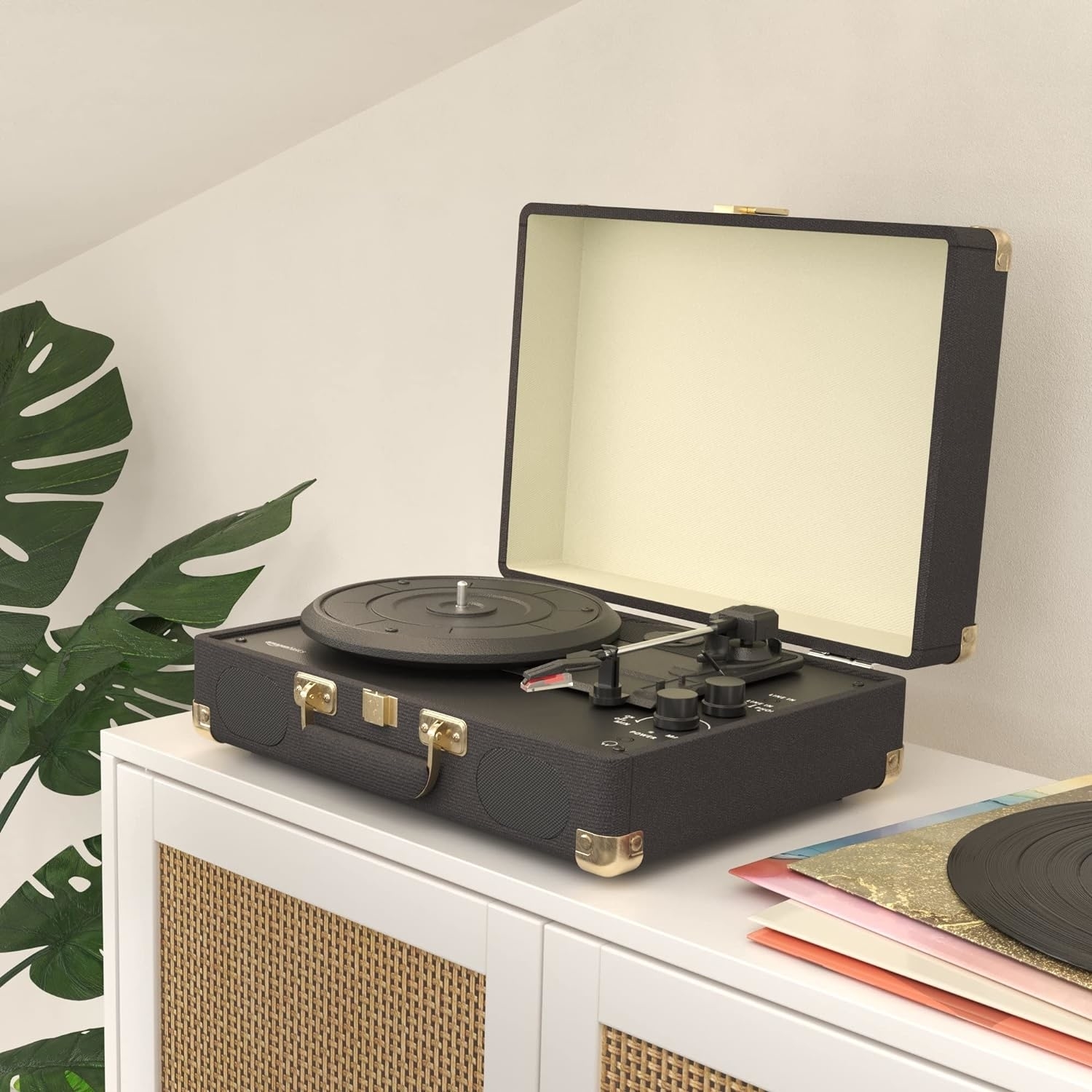 The black suitcase record player on a white cabinet