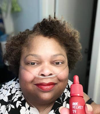 reviewer wearing red shade and holding the bottle