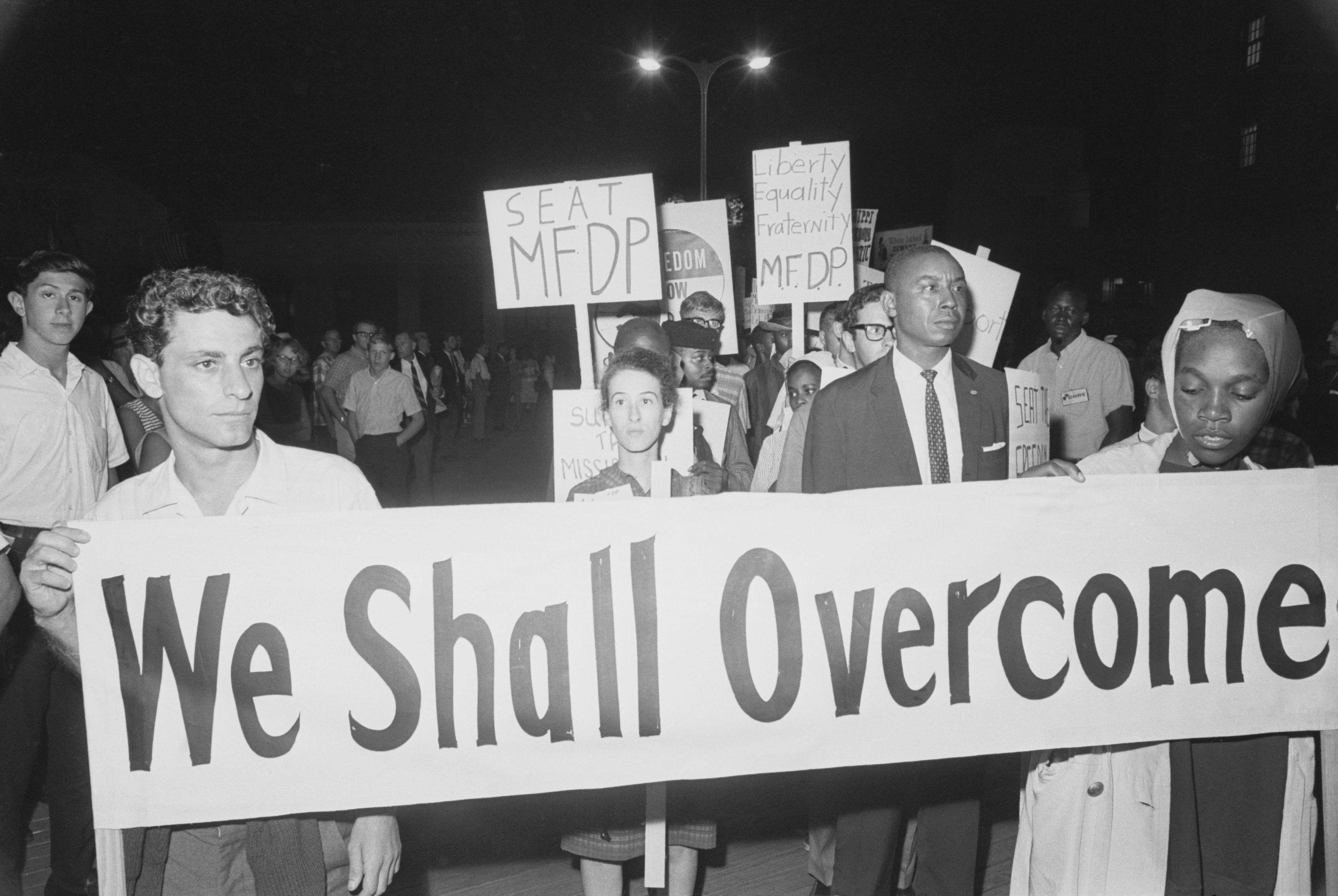 a 1960s protest with a sign saying &quot;we shall overcome&quot;