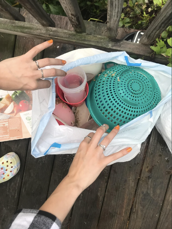 A garbage bag with a colander and other dishes and containers in it