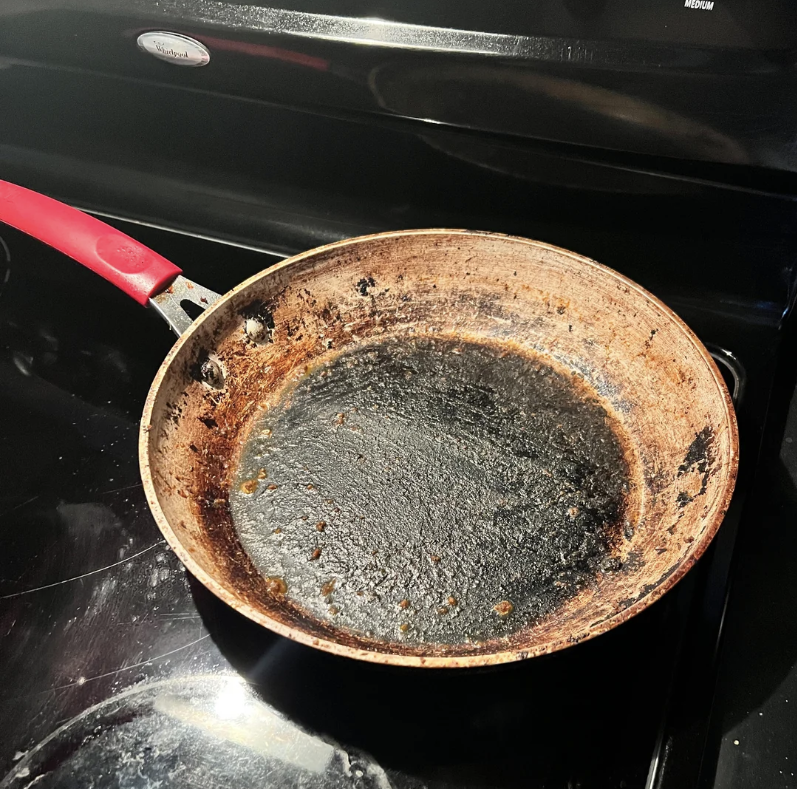 A pan on a stove with thick crud on it
