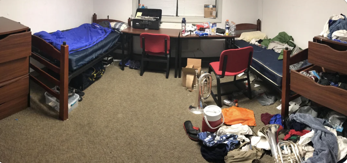 One side is clean, with a neat desk and items neatly underneath a twin bed, and the other has a messy desk and clothes and other items all over the rug