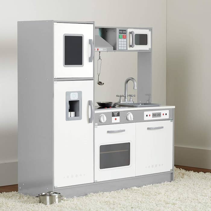 A white-and-gray toy kitchen with fridge, oven, microwave, faucet, dishwasher