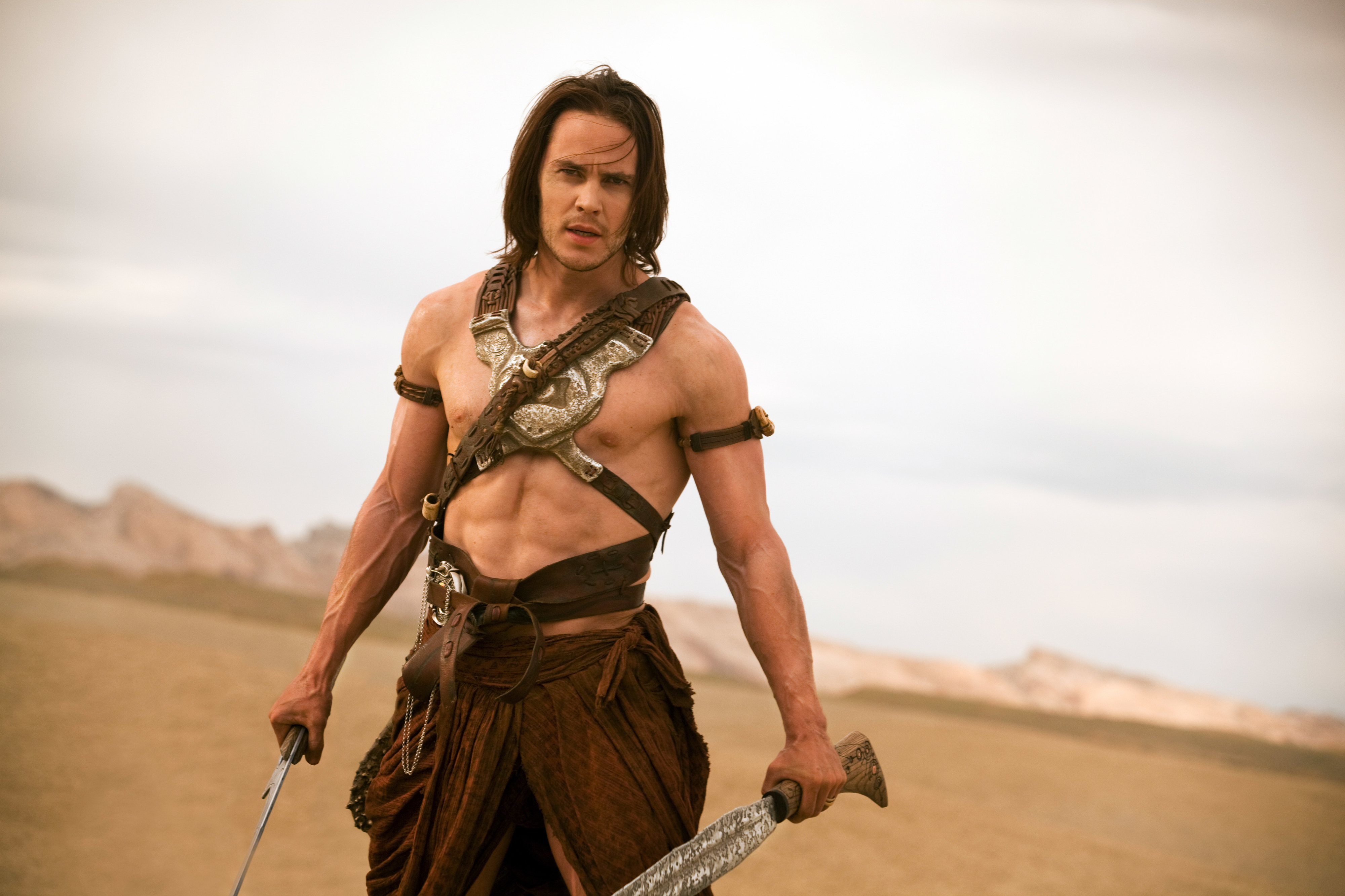 him dressed in warrior gear with no shirt and holding swords
