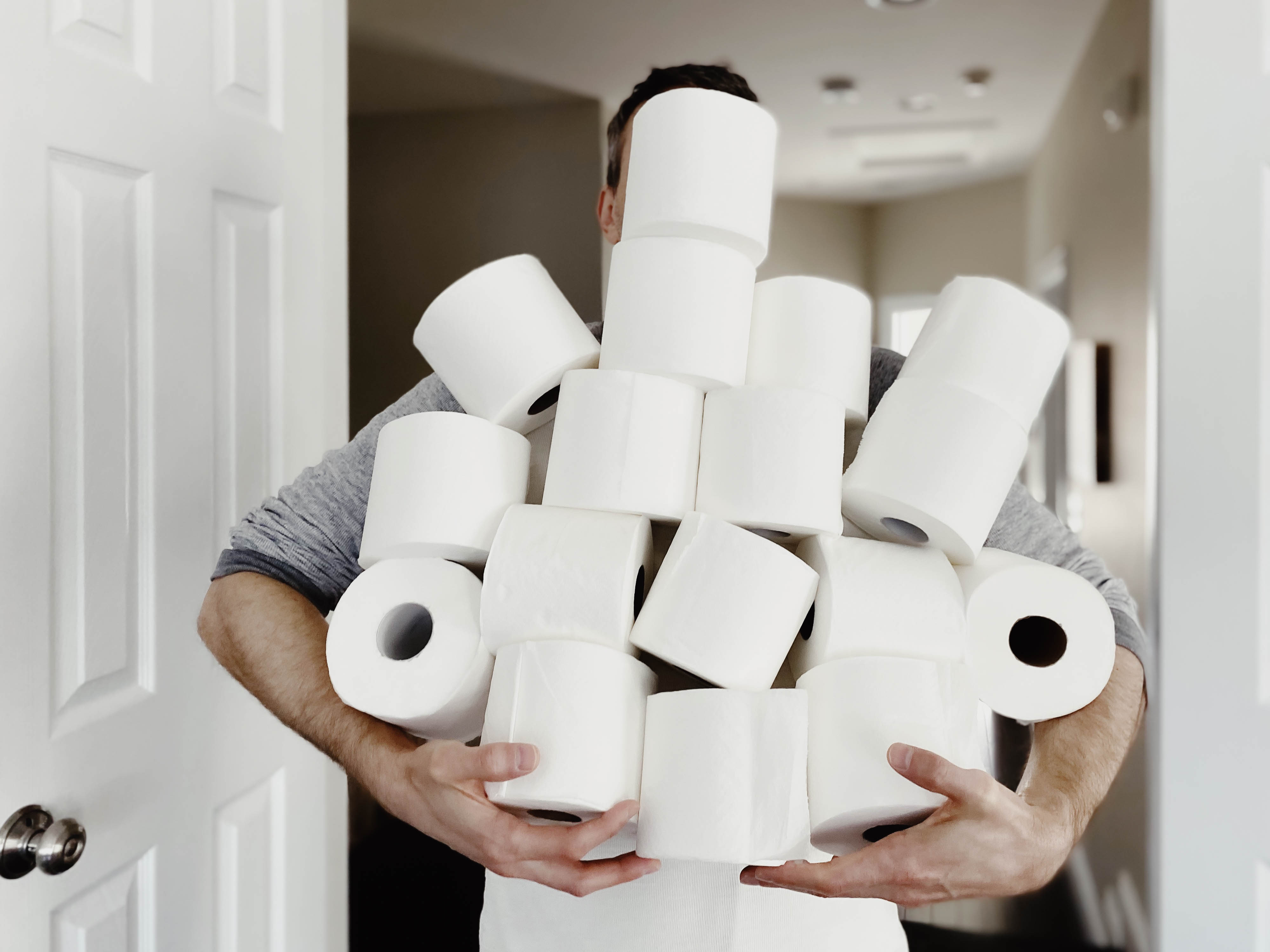 Person carrying an armload of toilet paper