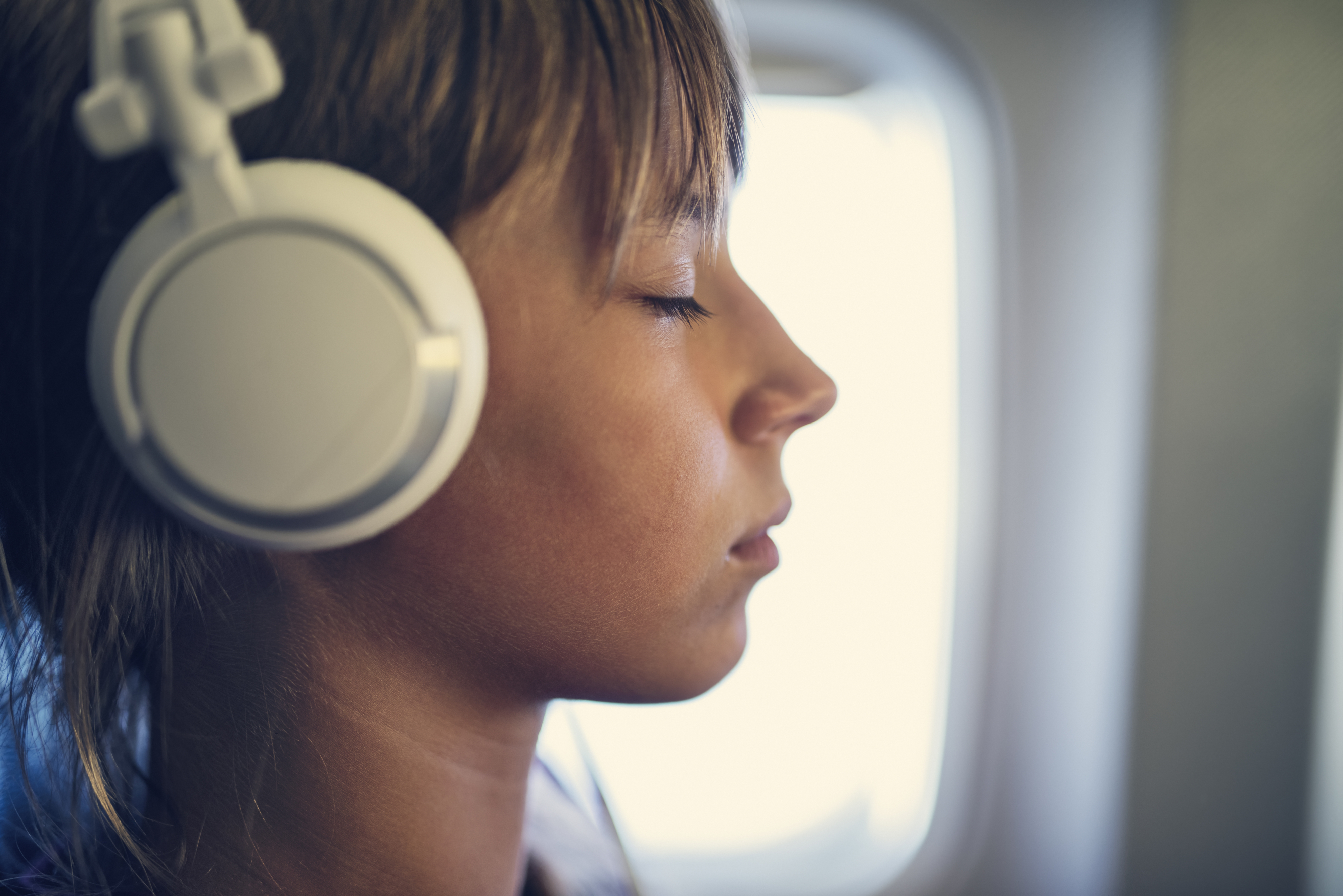 someone wearing headphones with their eyes closed on a plane