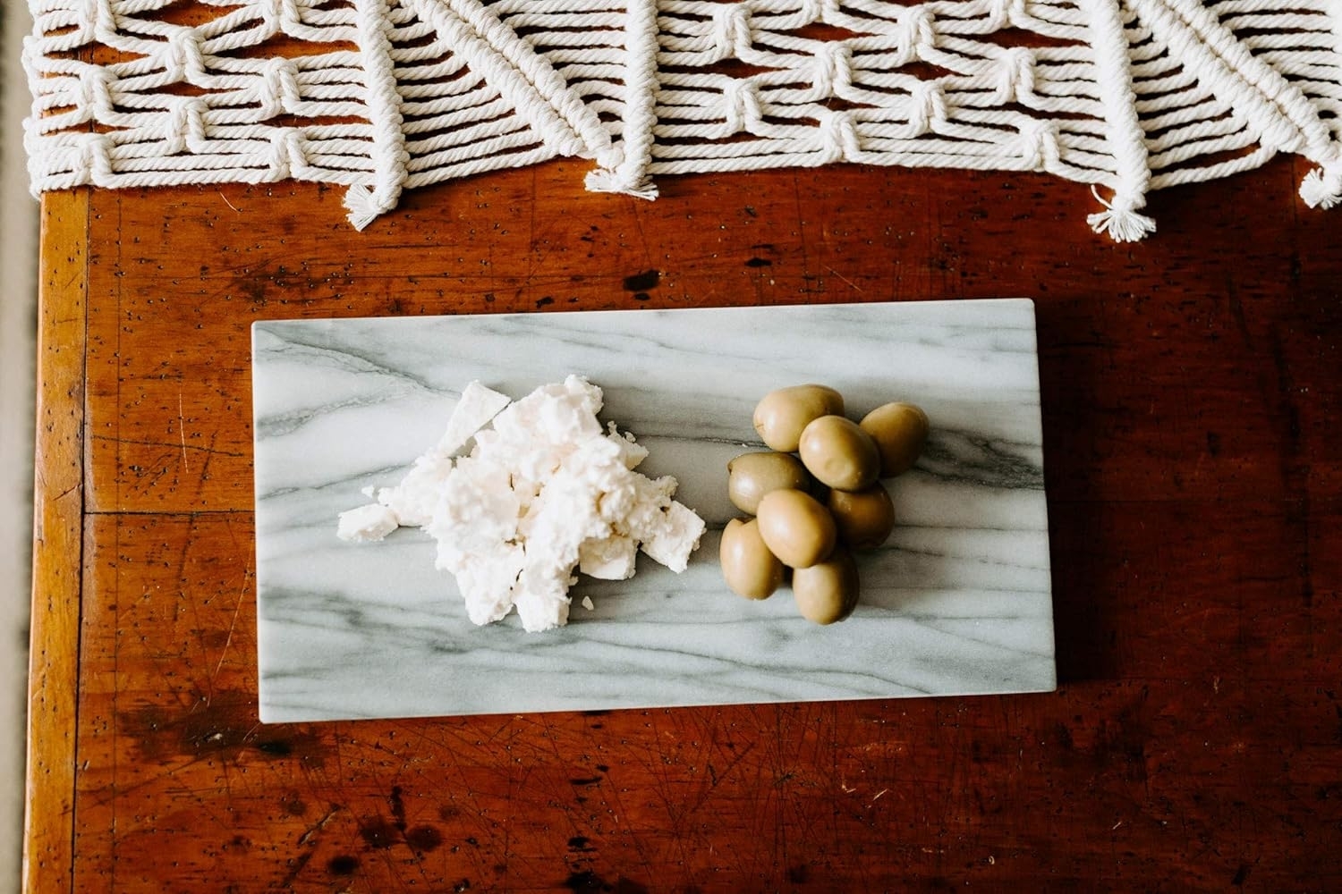 White and grey Marble rectangular cutting board with a wedge of cheese and some grapes