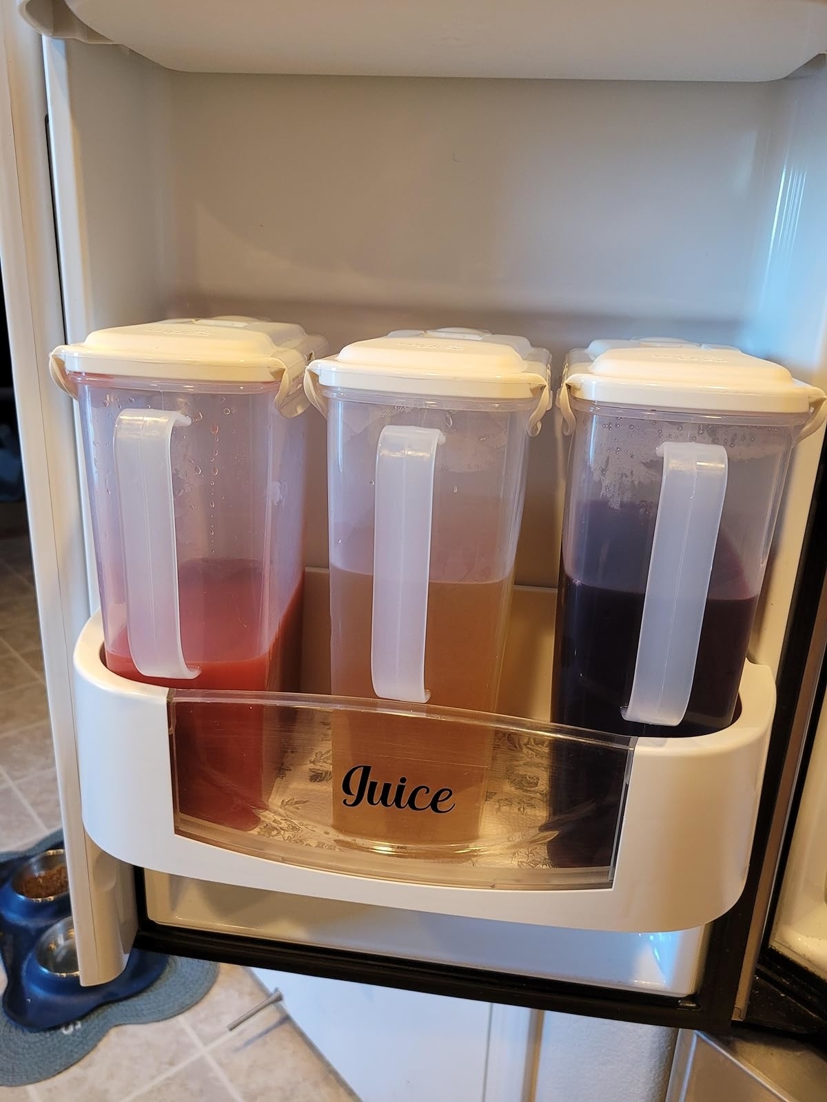 reviewer&#x27;s three slim pitchers filled with juice and store in the fridge door shelf