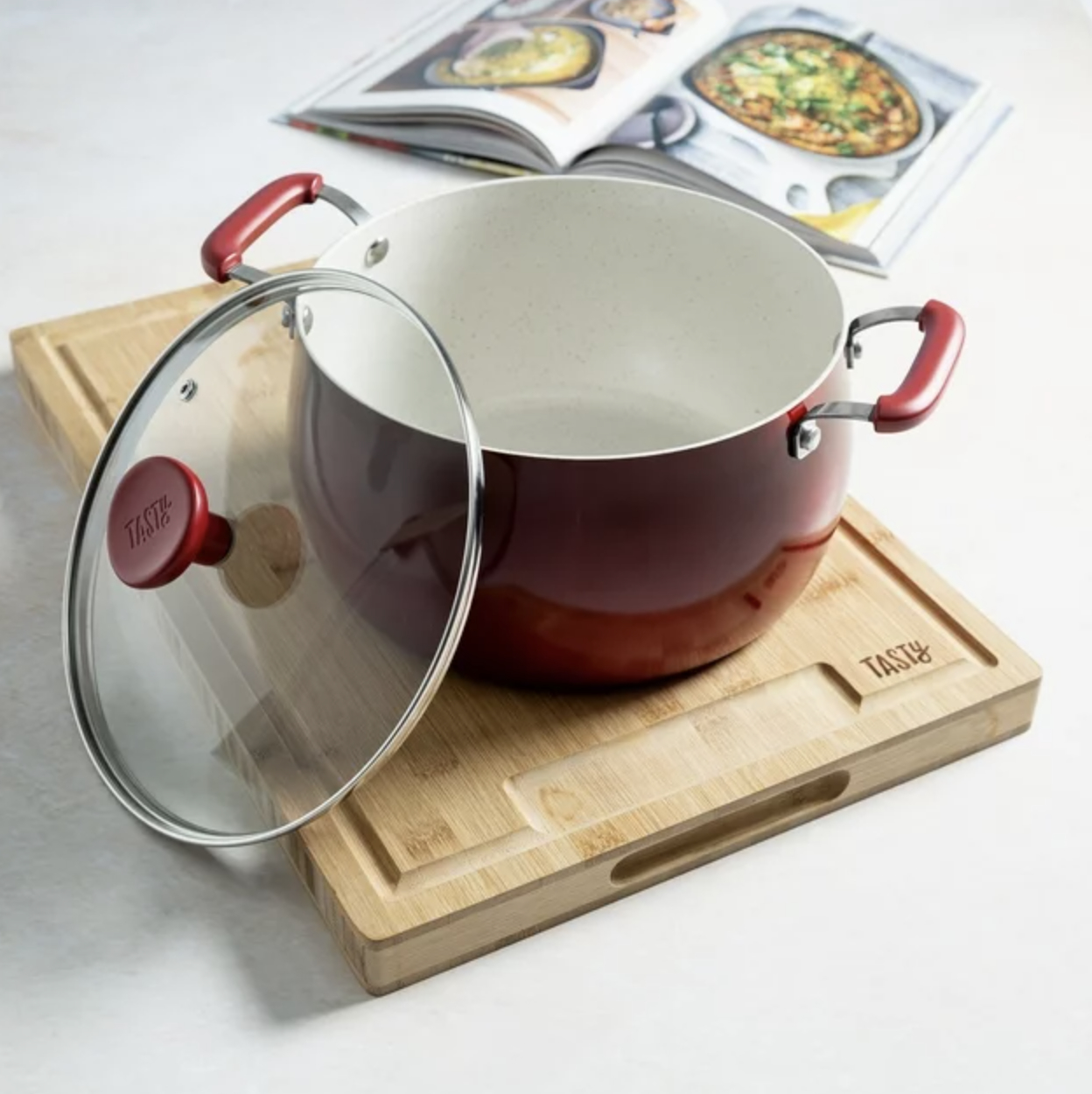 the red dutch oven on cutting board with glass lid resting against side of pot